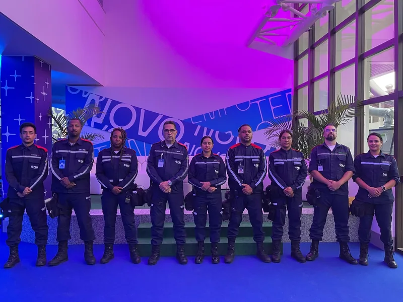 Equipe uniformizada do Grupo F&J em um ambiente interno com iluminação azul e violeta